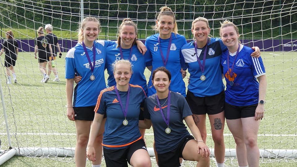 A group of women wearing blue football shirts in front of a goal at Hollywell Sports Complex, 麻豆視頻_麻豆直播_麻豆传媒官网